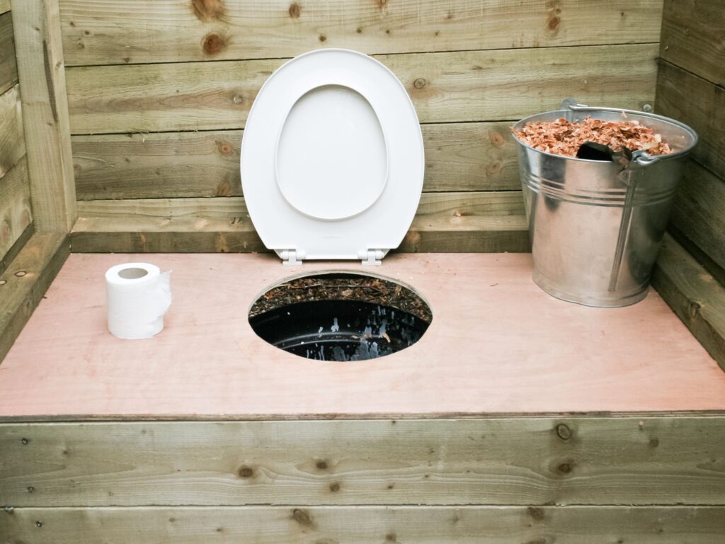 How does a composting toilet work? A compostable potty with a bucket of sawdust next to it.